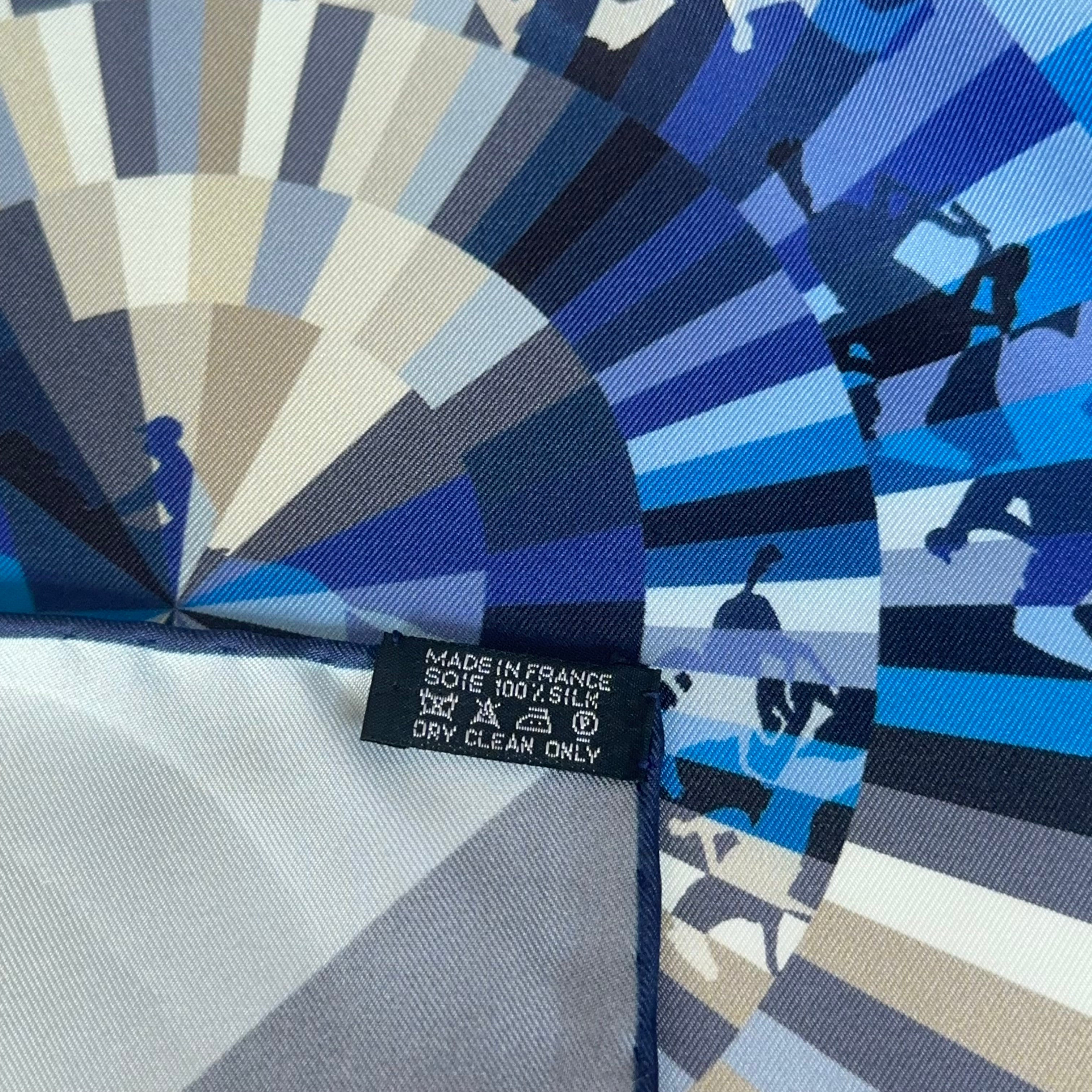 Étiquette d'entretien blanche standard "MADE IN FRANCE - SOIE" cousue sur le bord roulotté main bleu marine du carré.