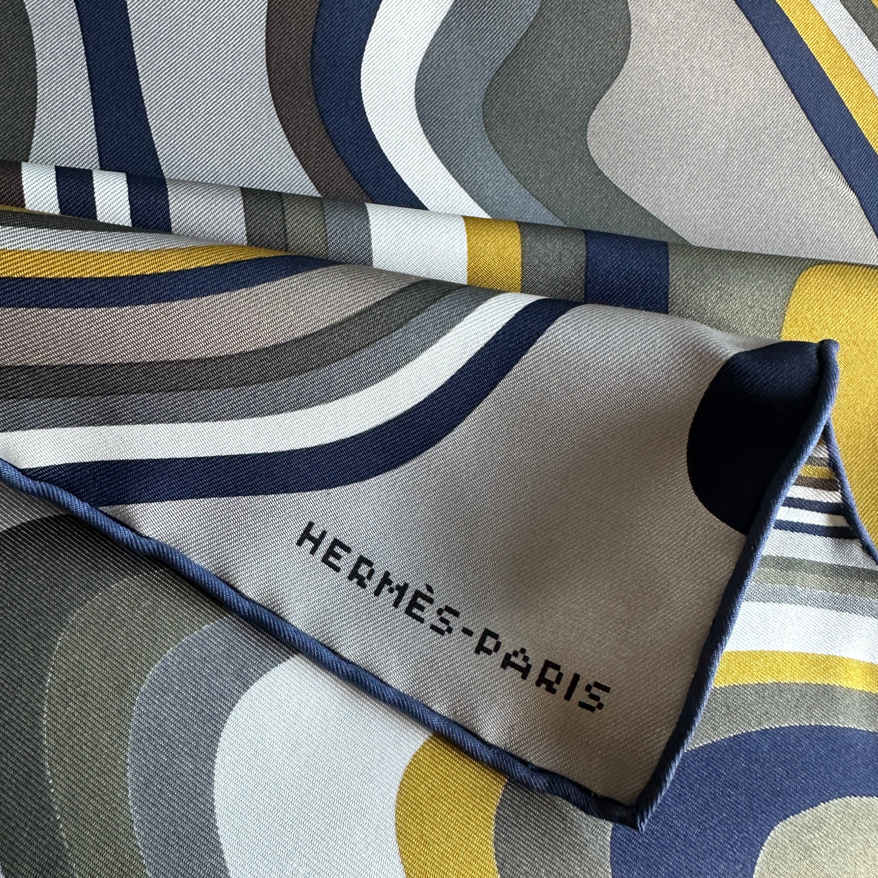 Signature de la marque "HERMÈS-PARIS" imprimée en typographie moderne pixelisée, clin d'œil à l'art numérique.