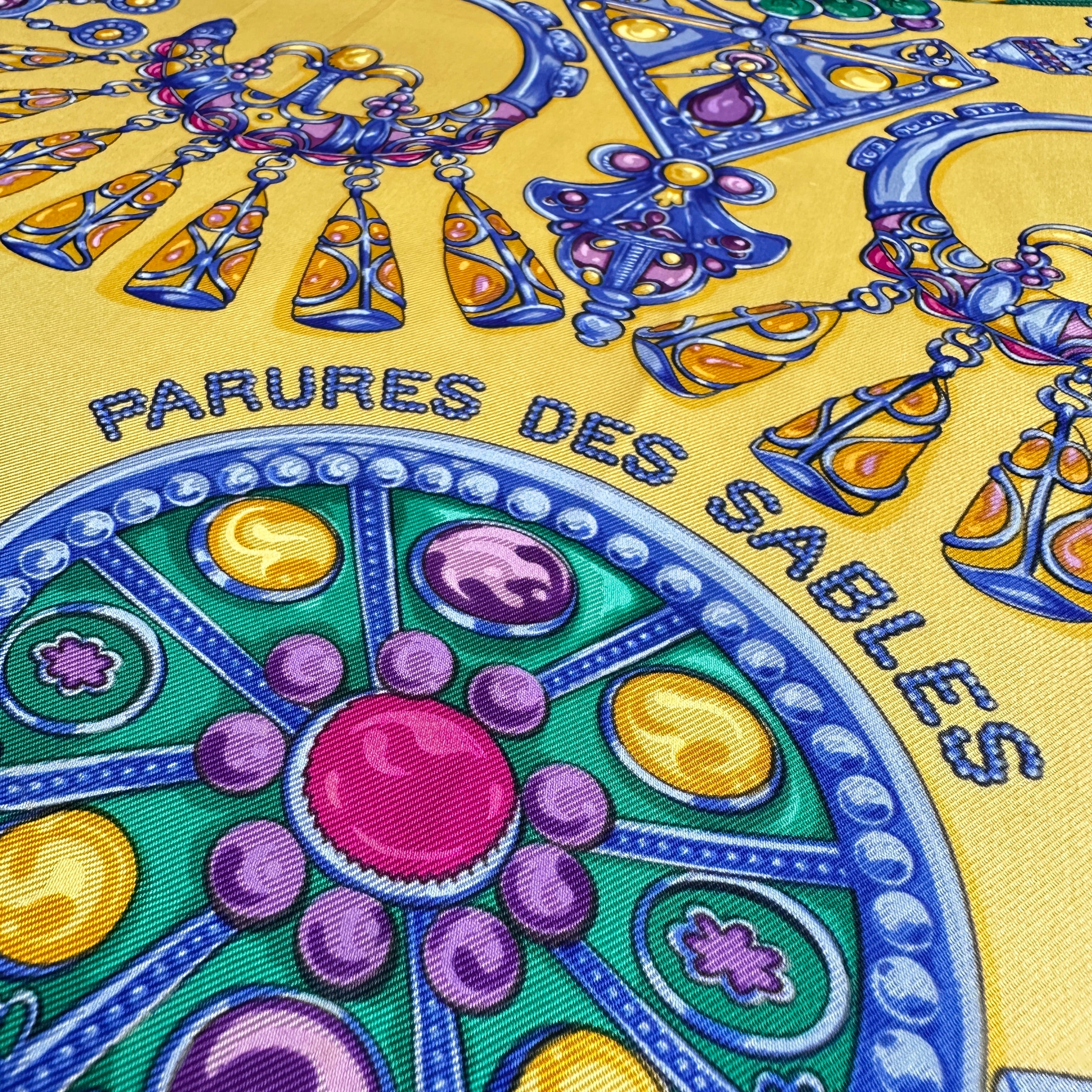 Gros plan sur le coin du foulard avec motif de bijou circulaire incrusté de pierres.